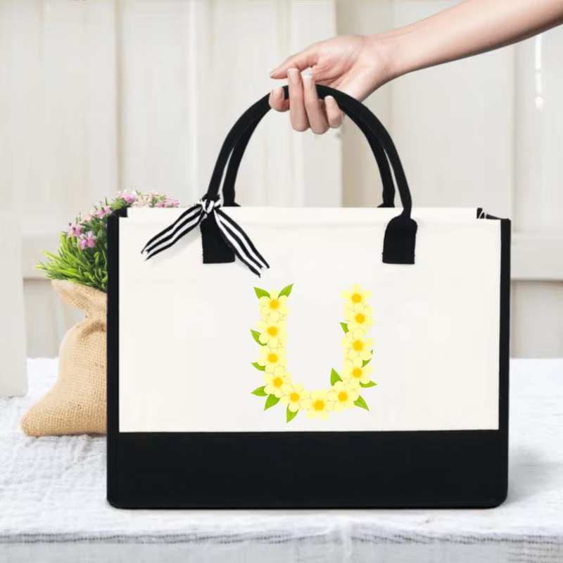 Les sacs fourre-tout en toile crème et noire avec des fleurs jaunes et un design lettre U sont parfa