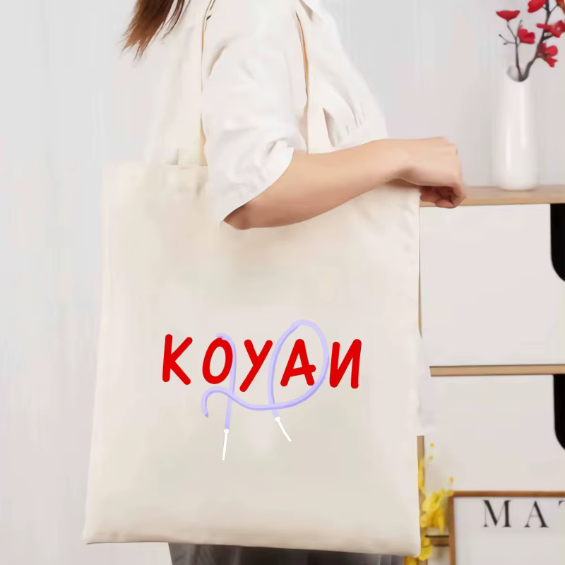 Un sac fourre-tout en toile de couleur crème avec texte Koyani et motifs de motifs abstraits pour un